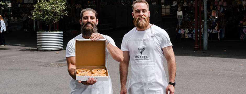 two men smiling and holding a dessert